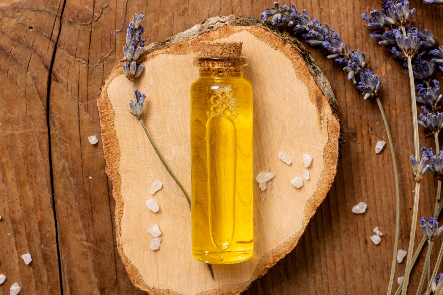 Duftöl-Fläschchen mit Lavendel auf Holz
