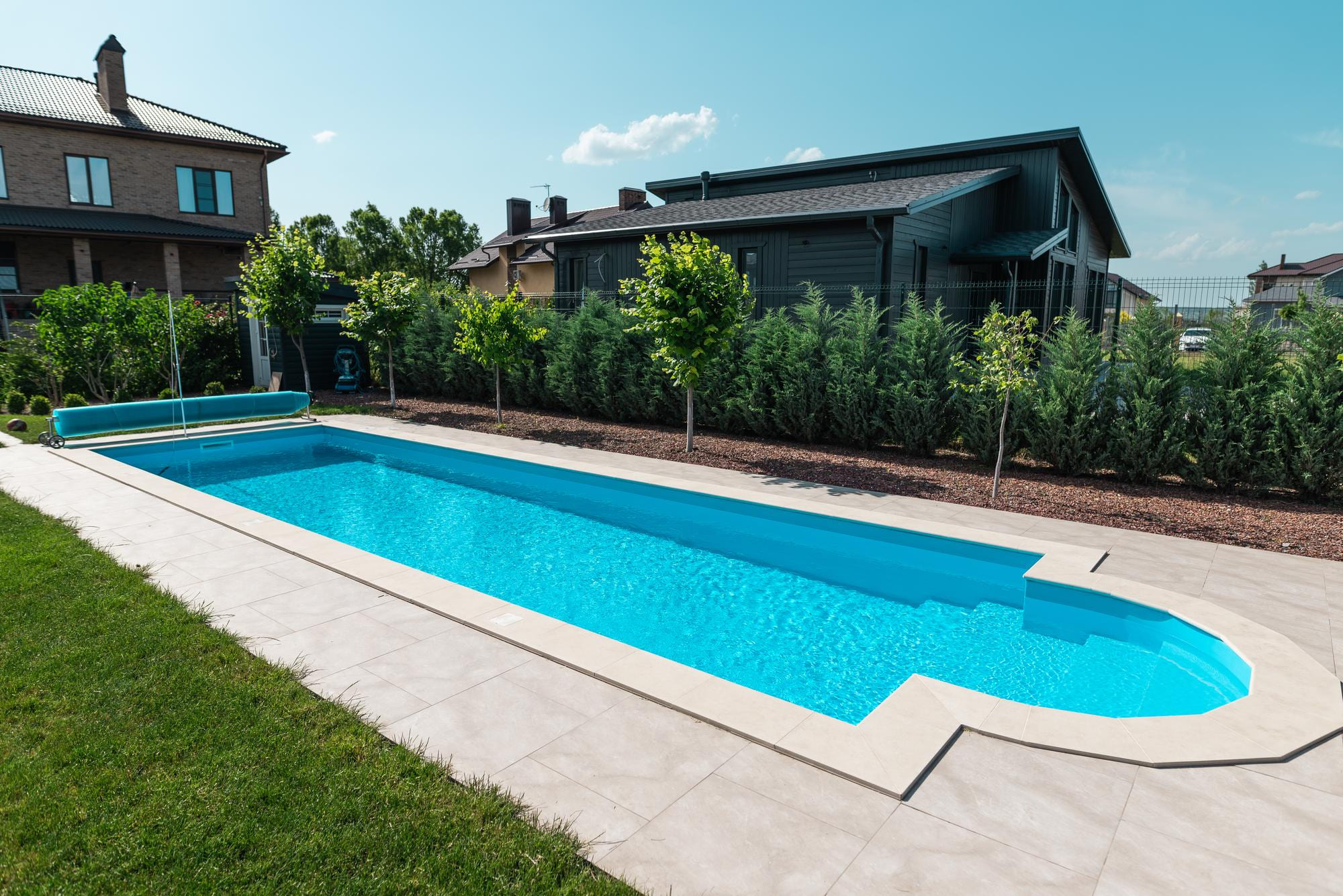 Moderner Pool mit heller Terrasse vor modernem Wohnhaus