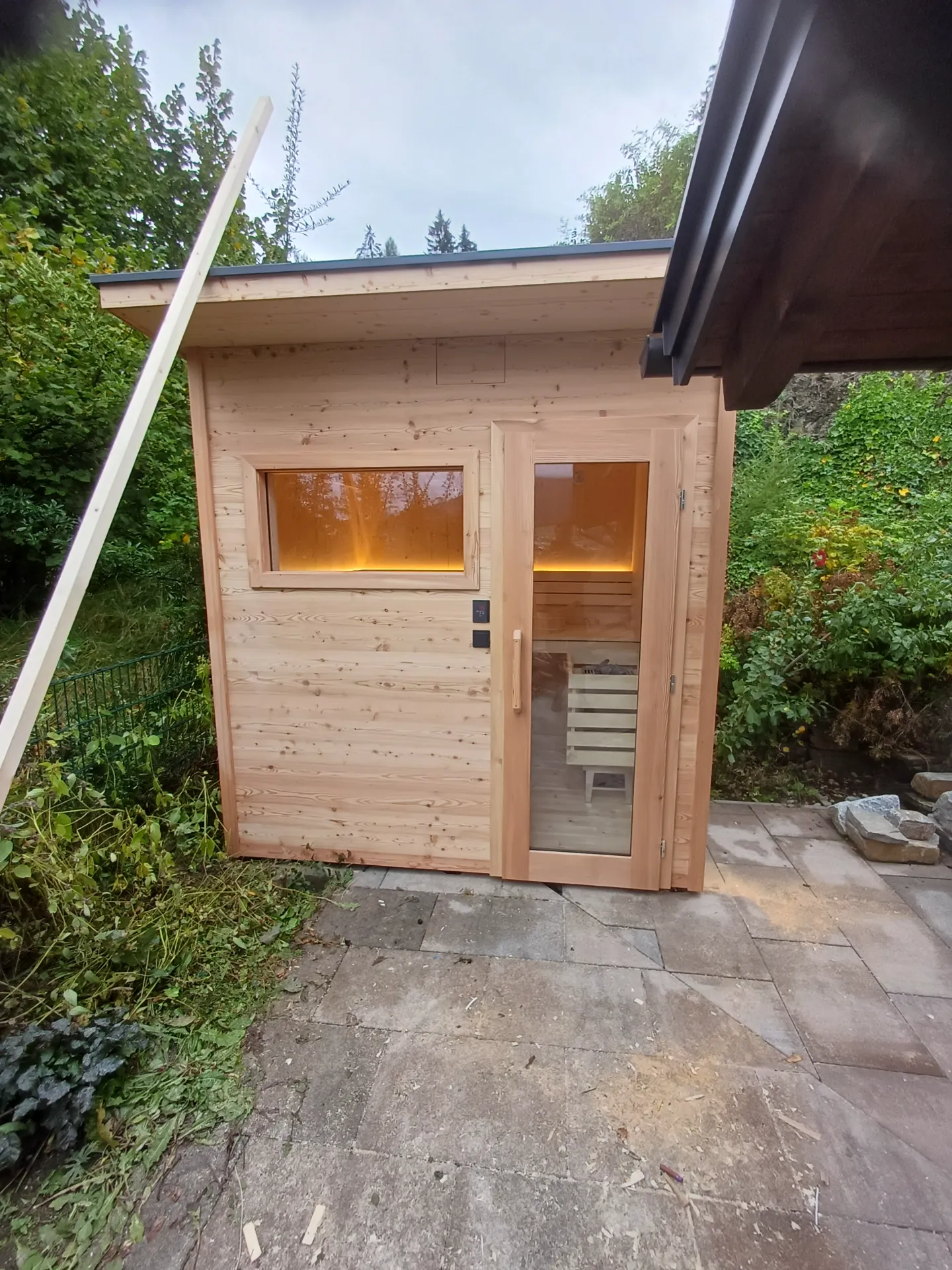 Neue Außensauna aus Lärchenholz mit Glastür im Garten